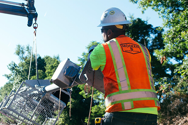 Two workers in vests displaying the Modern Railways Logo.